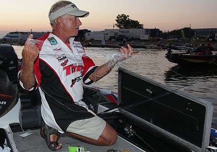 Steve Daniel takes worn line from one of his reels. He sits in a three-way tie for 71st place.