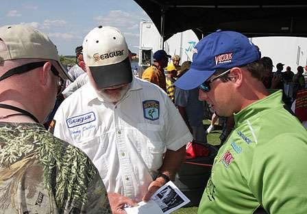 Day One co-angler leader Steve Wisdom (right) was giving an interview to Lynne Burkhead (left) when he realizes that Jimmy Dudley (center) has just pushed him out of the Day Two lead.