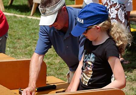 Darren Warren helps his daughter Ashley put the finishing touches on her wooden bass cut-out at the Toyota Tundra 