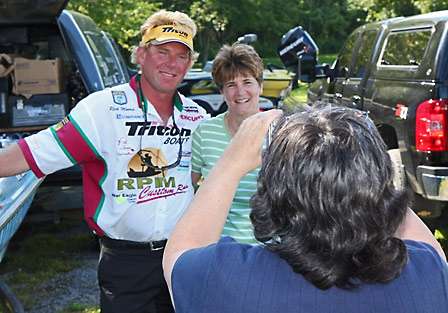 Rick Morris hops down from his boat in Angler Alley to pose with Marge Curtis while Marie Colorito takes their photo.