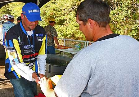 Bradley Hallman signs an autograph just before walking on stage to weigh his fish. Hallman would fall to 12th place going into the final day.