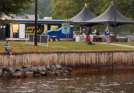 A young fan sits on a retaining wall on the shores of Lake Guntersville as the field is launched to start the first day of competition.
