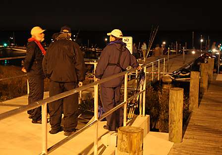 Co-anglers share stories in the pre-dawn darkness as they wait at the docks for their pro partners to launch.