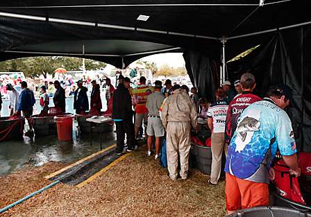 Anglers stand in the weigh-in line under the tents, but it offers little relief from the constant rain.