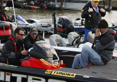A photographer watches Kevin VanDam and Kevin Wirth share a moment at the console of VanDam's boat.