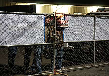 Fans peer through the fence at the boat yard in the parking lot at the Red River Marina.