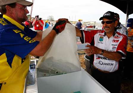 Paul Elias brings his fish to the bump table and hands them to BASS official Max Leatherwood for measuring.