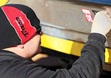 Cory Schmidt places stickers and registration decals on a Triton boat that can be used if one of the competitors has a breakdown during the 2008 Bassmaster Classic.