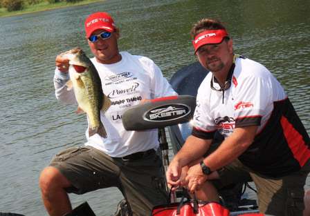 Pro Cliff Crochet holds up his kicker bass as his co-angler helps him bag his fish.