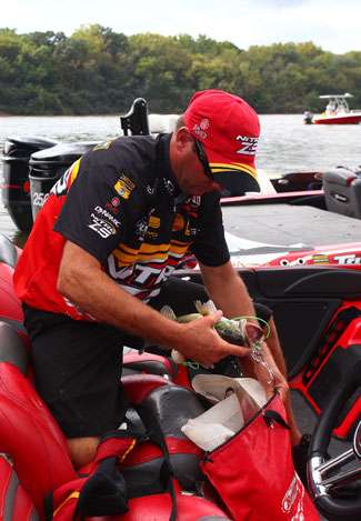 Kevin VanDam slips an Alabama River spotted bass into his weigh-in bag before heading up the dock.