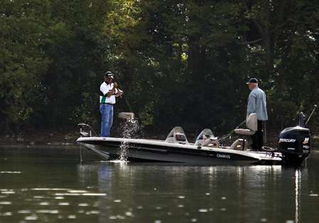 Brett Mitchell snatches a small bass into the boat as his co-angler Tommy Swindle watches.