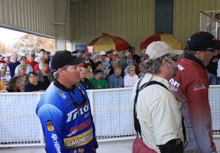 Anglers from the first flight line up at the tanks to the side of the stage as fans watch the weigh-in get started.