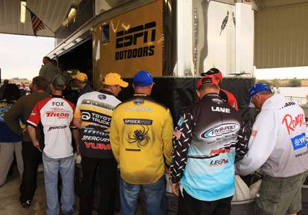 The final pro anglers stand at the tanks to the side of the stage, trying to sort out who might have the most weight.