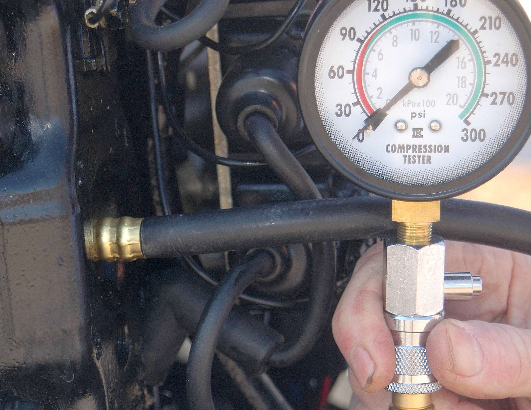 Screw the compression tester into the spark plug hole. Disconnect the kill switch or the ignition battery so the engine can't start. Then turn the engine over for three to four seconds.