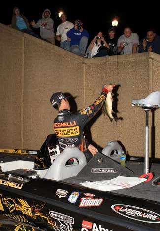 Pro Michael Iaconelli shows off his largest bass to the crowd hanging over the side of the wall at the vehicle entrance to the building. 