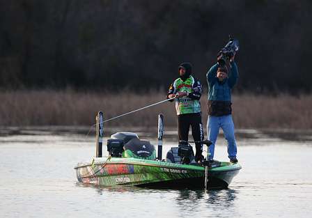 Tournament-leader Byron Velvick reels in a cast as his ESPN cameraman films the action.