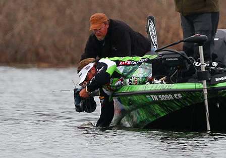 As cameras film the action, Velvick reaches down to cradle the fish and pull it on board.