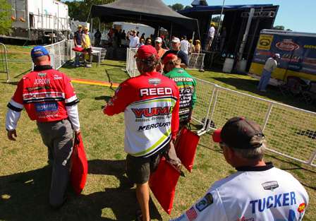 A group of Elite Series anglers walk up toward the fish-check station behind the weigh-in stage.