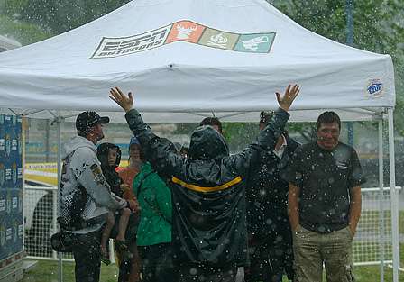 A group of anglers and fans huddle in the tent, while one enthusiastic fan enjoys the downpour.
