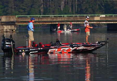 Randy Howell fishes offshore while Britt Myers boats a fish over his shoulder near a bridge. 