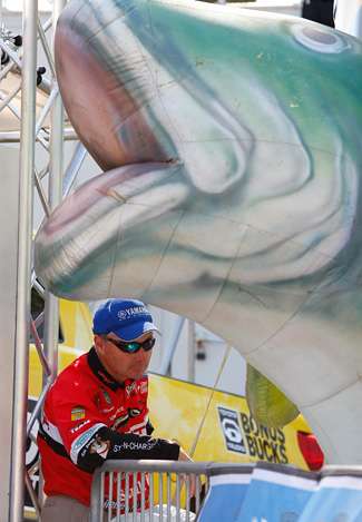 Mark Menendez watches the weights cross the scales and he ducks next to a giant blow-up bass next to the stage.
