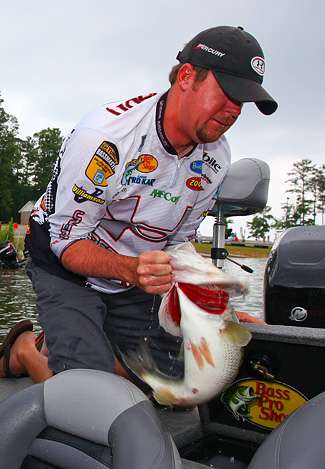 Jason Williamson grabs the biggest bass of the tournament out of his livewell as it flops wildly in his grasp.