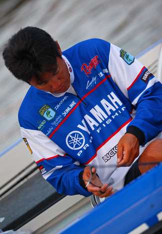 Takahiro Omori cuts his line with scissors while getting his tackle ready for a day of fishing.