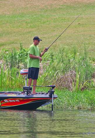Counter to his power fishing roots, Kevin VanDam trolls down the edge of shallow grass with a big flipping stick in his hand on a hot summer day on Lake Jordan.