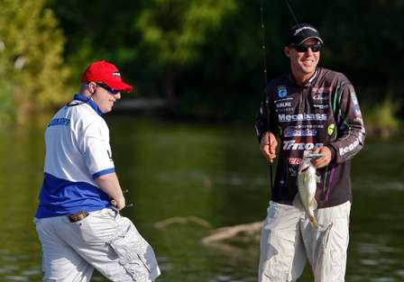 Aaron Martens catches a small bass as his partners, Bob Cauthon watches.