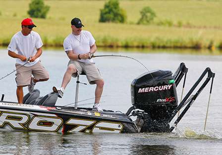 Tim Murray hooks up with a monster bass that thrashes next to the boat as Edwin Evers scrambles to help him land it.