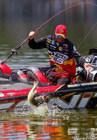 As Kevin VanDam bends down to grab the bass, it makes one last desperate jump next to the boat.