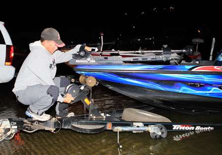 Elite Series pro Jeff Reynolds kneels precariously on his trailer as he unhooks his boat for launch.