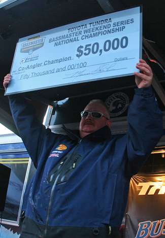 Dennis McGouirk holds up the check for $50,000 that he received as non-boater winner.