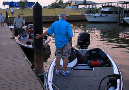 Gaylon Heard (foreground) and John Renard watch a bass near the dock as it chases baitfish in the early morning light.