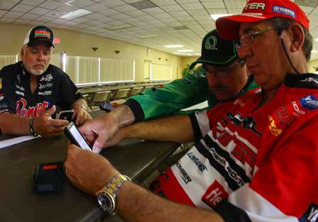 Tommy Biffle, Zell Rowland, and Shaw Grigsby compare notes from lake maps loaded onto their cell phones. 