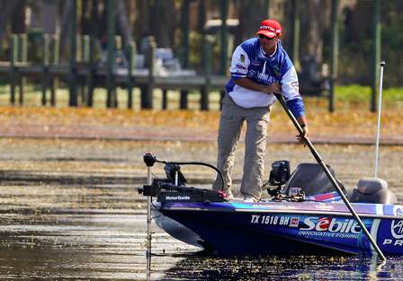 Todd Faircloth spots a bass on a bed and uses his push-pole to stop the boat. 