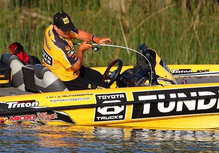 Scroggins moves to the driver's seat of his boat to land the fish. 