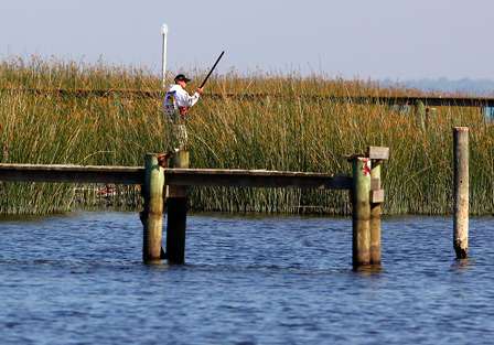 Edwin Evers poles his boat through the bulrushes and boat docks along the shoreline of Crescent Lake. 