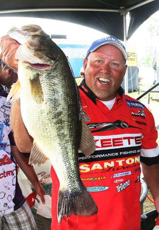 Matt Herren holds up his largest bass behind the weigh-in stage.
