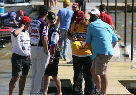 Anglers sign autographs while waves rock the dock they are standing on.