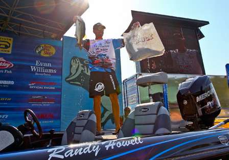 Randy Howell stands tall on the back deck of his boat and shows off his biggest fish of the day.