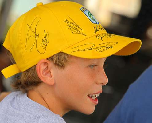 <p>
	A young volunteer covers his hat with autographs.</p>
