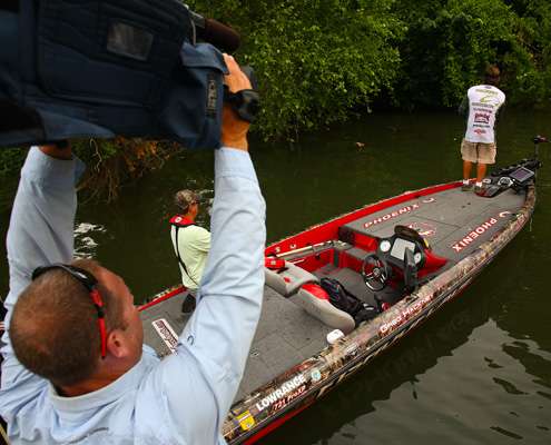 Camera man Brian Mason raises his camera high to get a different perspective of Greg Hackney fishing.
