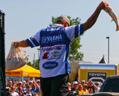 With a sack of fish in one hand and his biggest bass of the day in the other, Russ Lane steps from his boat to the stage.
