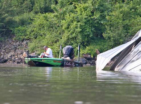 <p> 	Bill Lowen works on getting a new lure ready as the current pushes him by a piece of trash in the water.</p> 