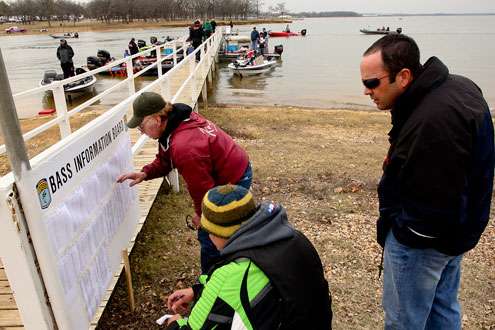 <p>
	Co-anglers check the B.A.S.S. information board for their Day Two pairings.</p>
