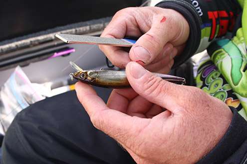 <p>
	After four days of abuse, Chapman uses his well-weathered hands to sharpen the hooks on a jerkbait.</p>
