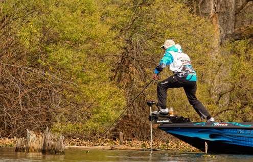 <p>
	Randy Howell climbs aboard his trolling motor to make a pitch under an overhanging bush. </p>
