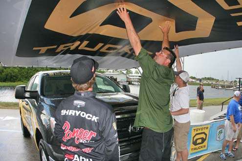 <p>
	Mark Zona and Fletcher Shryock move to hold up the roof of the Toyota Tundra Hooked Up! stage. The weight of the rain and wind had forced the roof to slide down.</p>
