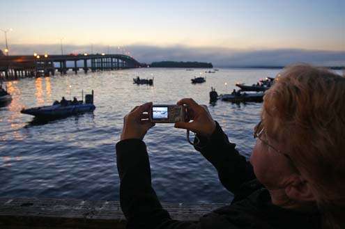 <p>
	A fan takes pictures from the shore, while anglers get ready for the start of the tournament.</p>
